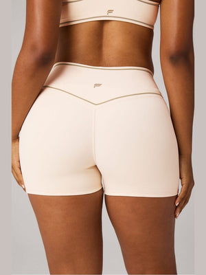 Fabletics No-Seam PureLuxe TLC biker shorts in peach with olive stitching, back view showing hidden scrunch and seamless glute lift